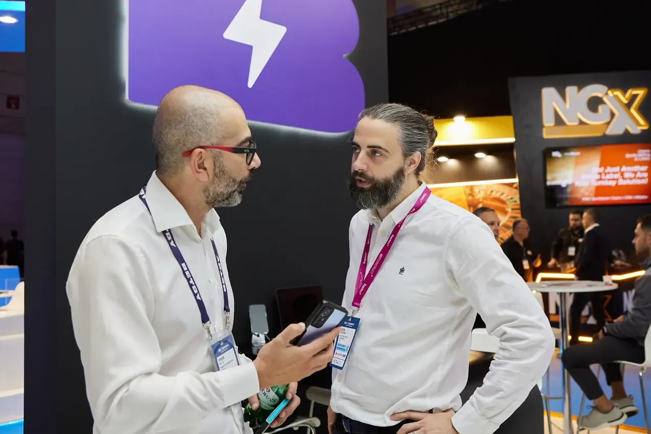 Two visitors talking at the Betby stand