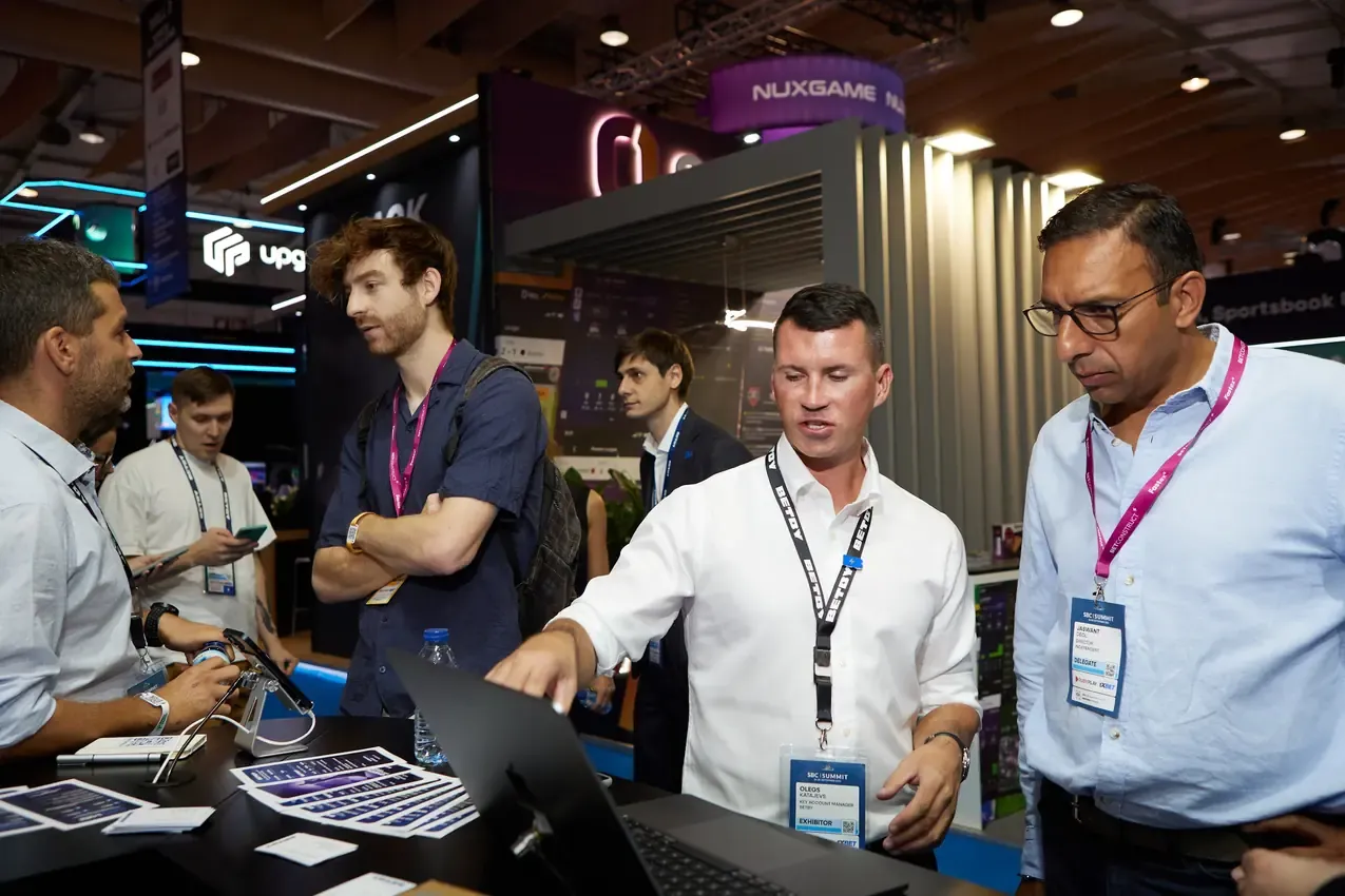 Group demo around a laptop at the Betby stand, SBC Summit 2024
