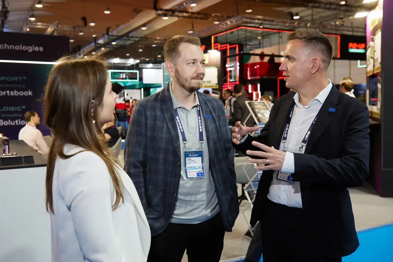 Betby representatives talking with a visitor on the show floor