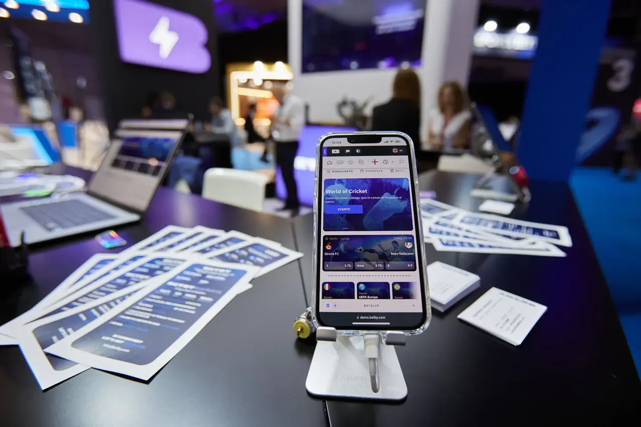 Betby product on a phone next to printed materials at the stand