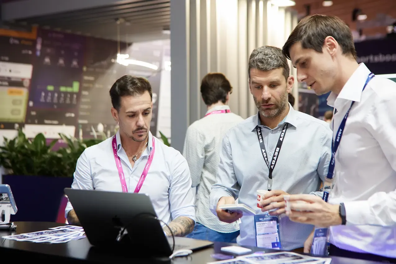Group around a laptop at the Betby stand, SBC Summit 2024