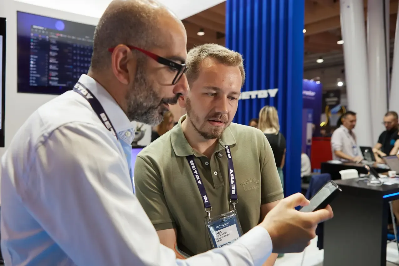 Two visitors reviewing the Betby platform on a phone