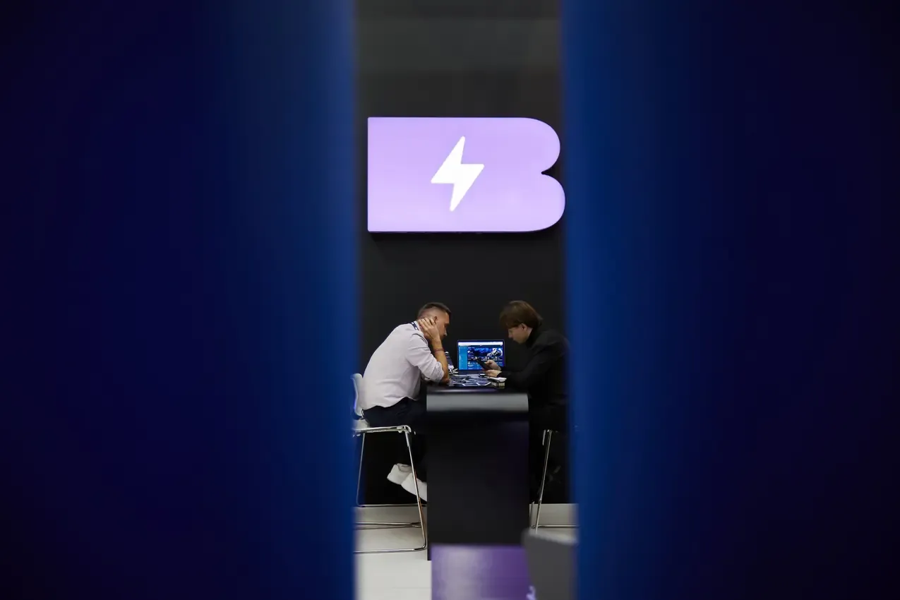 Two people at a laptop under the Betby logo wall at SBC Summit 2024